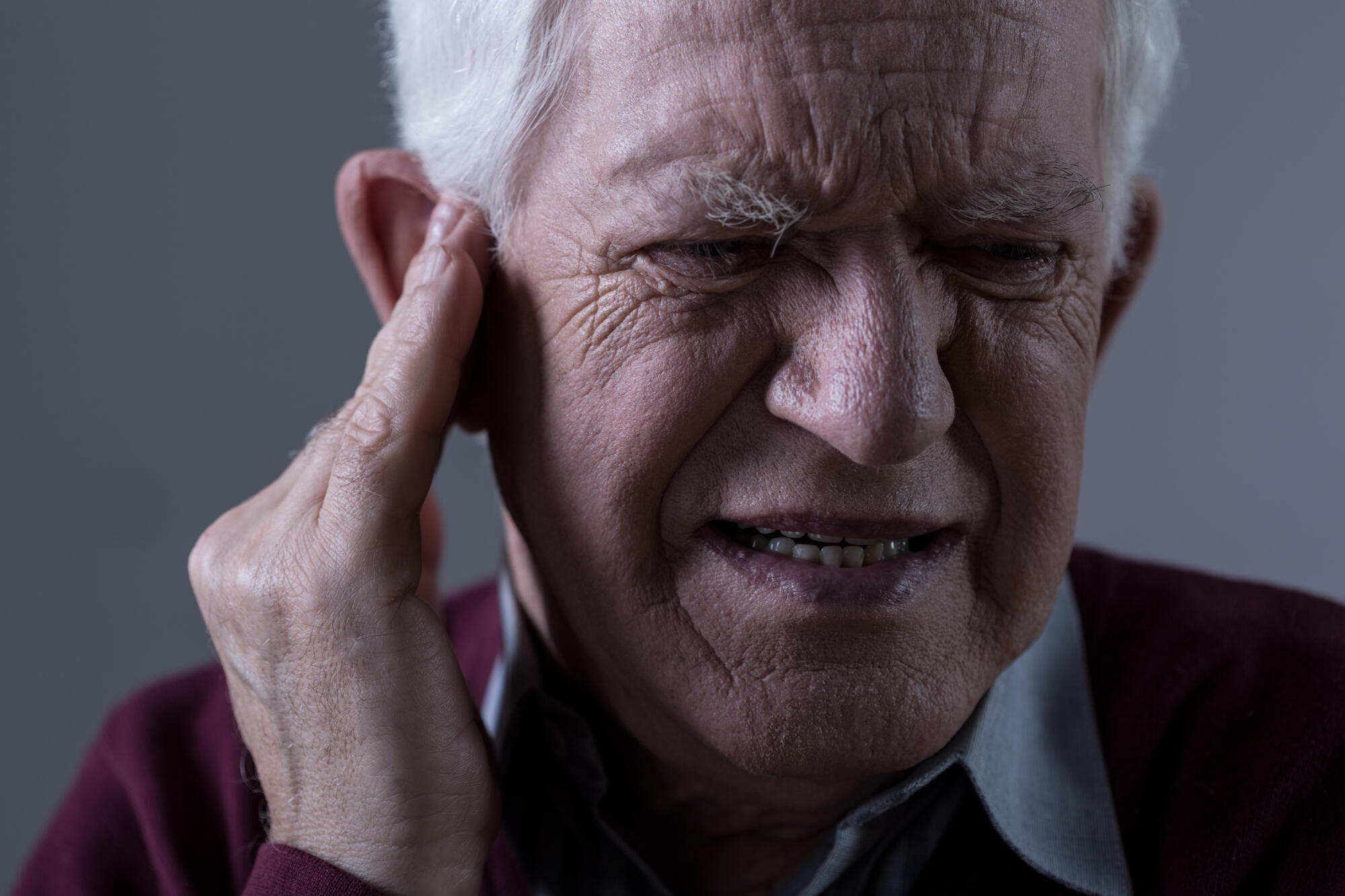 Elderly man holding ear in agony